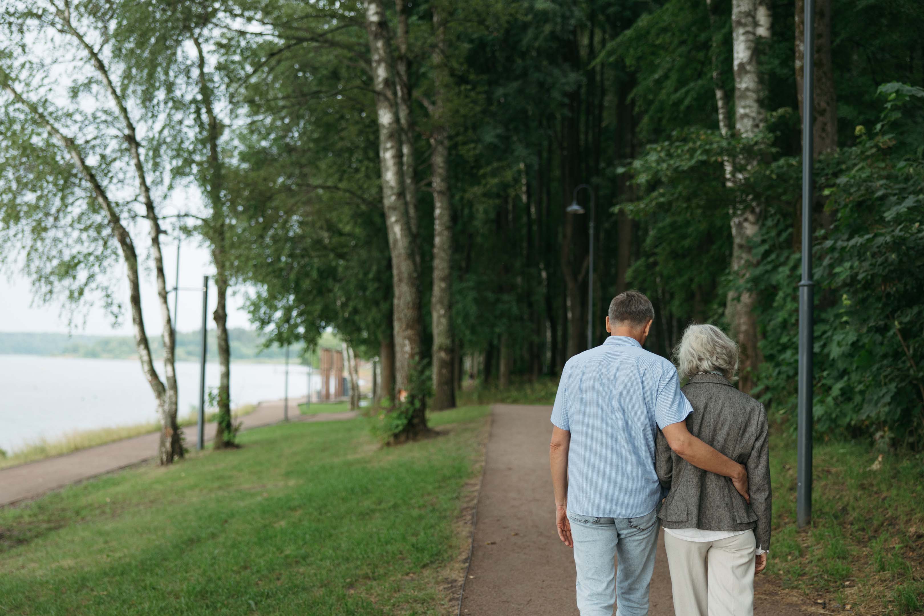 Two people walking together with their arm around each other showing support