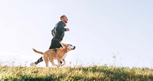 Person in sports gear running with their dog in nature