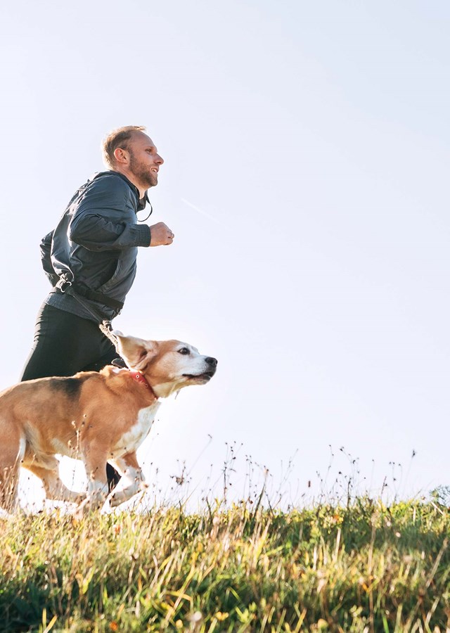 Person in sports gear running with their dog in nature