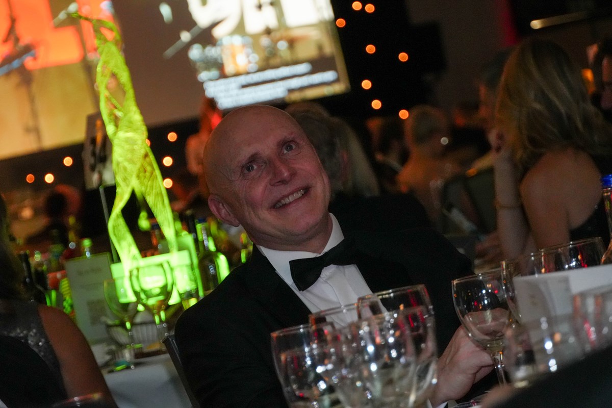 Smiling guest in a dinner jacket and bow tie at a table of wine glasses during the Ben Ball