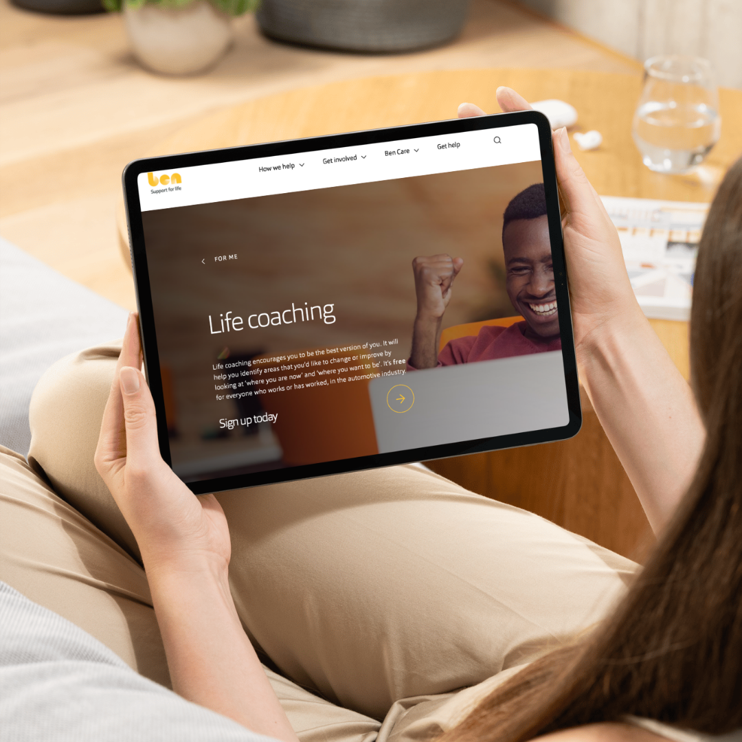 Woman holding a tablet showing Ben's 'Life coaching' web page with a 'Sign up today' link.