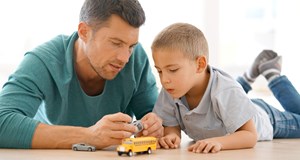 Father and son playing with cars together on the floor