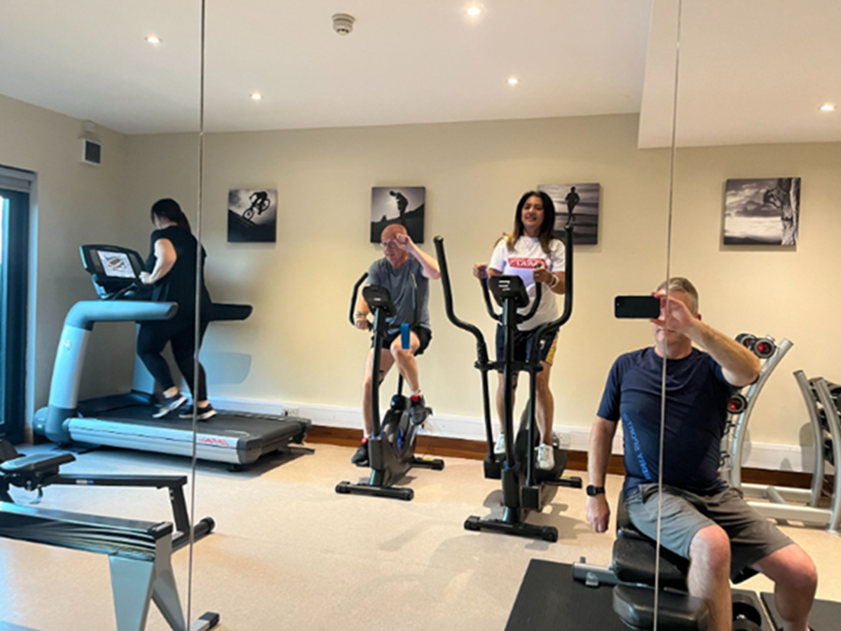 Team members taking part in a gym challenge, using an exercise bike, cross trainer, treadmill and rowing machine.