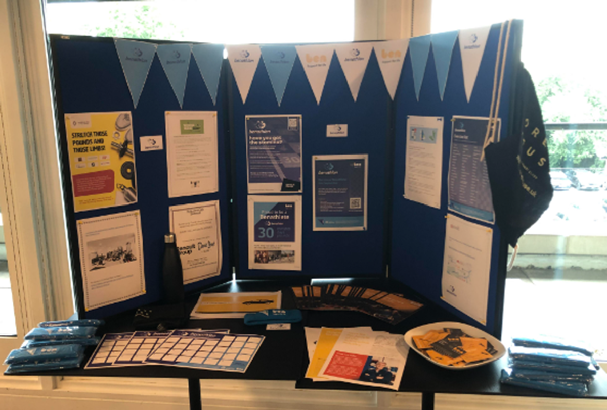 Blue and white Ben display stand on a table with leaflets, pens, wristbands and Benathlon posters and information sheets.