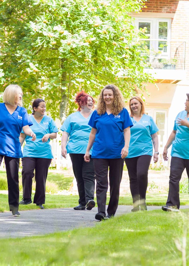 Group of carers walking and laughing through grounds of care centre
