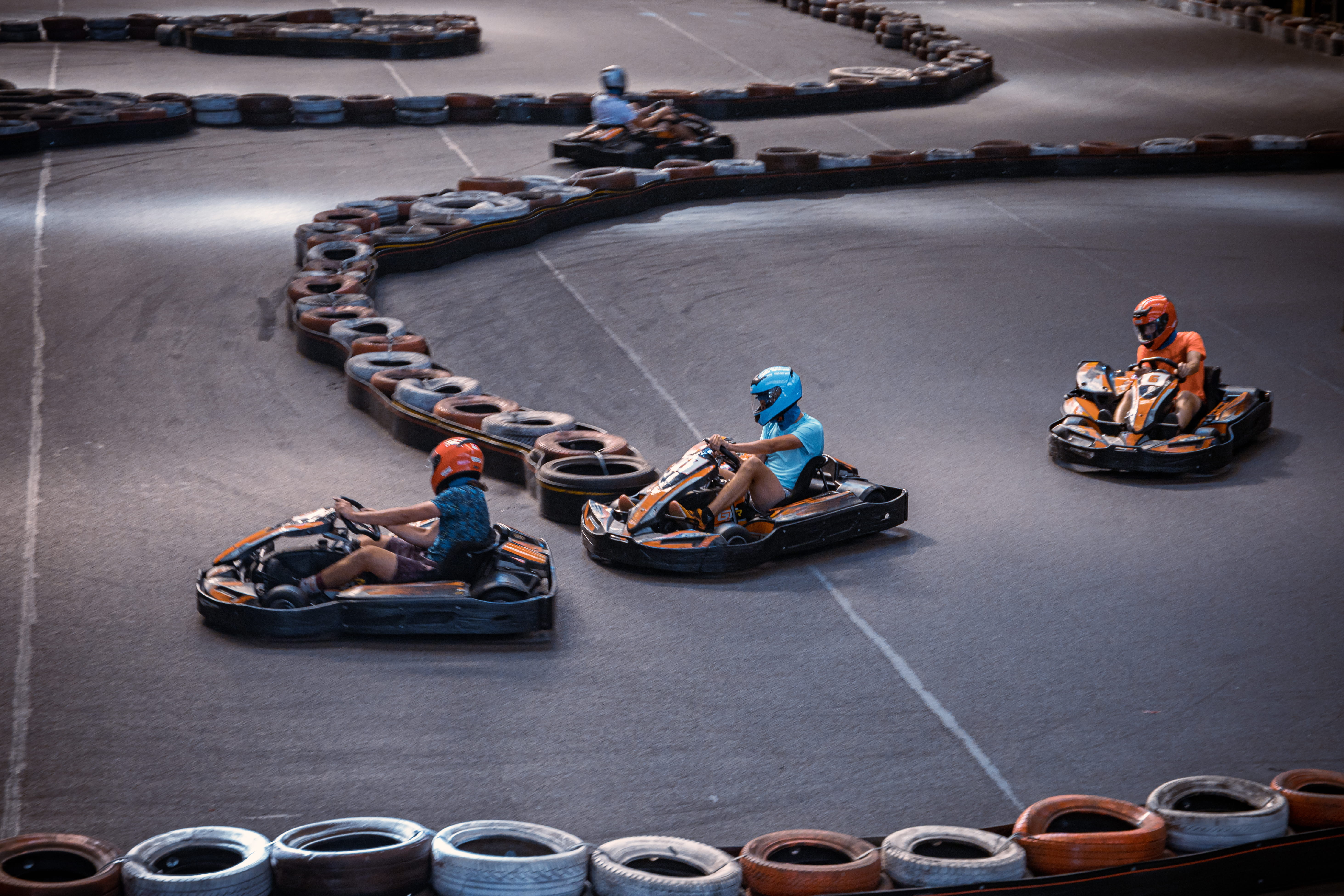 Three people overtaking each other on an indoor karting track