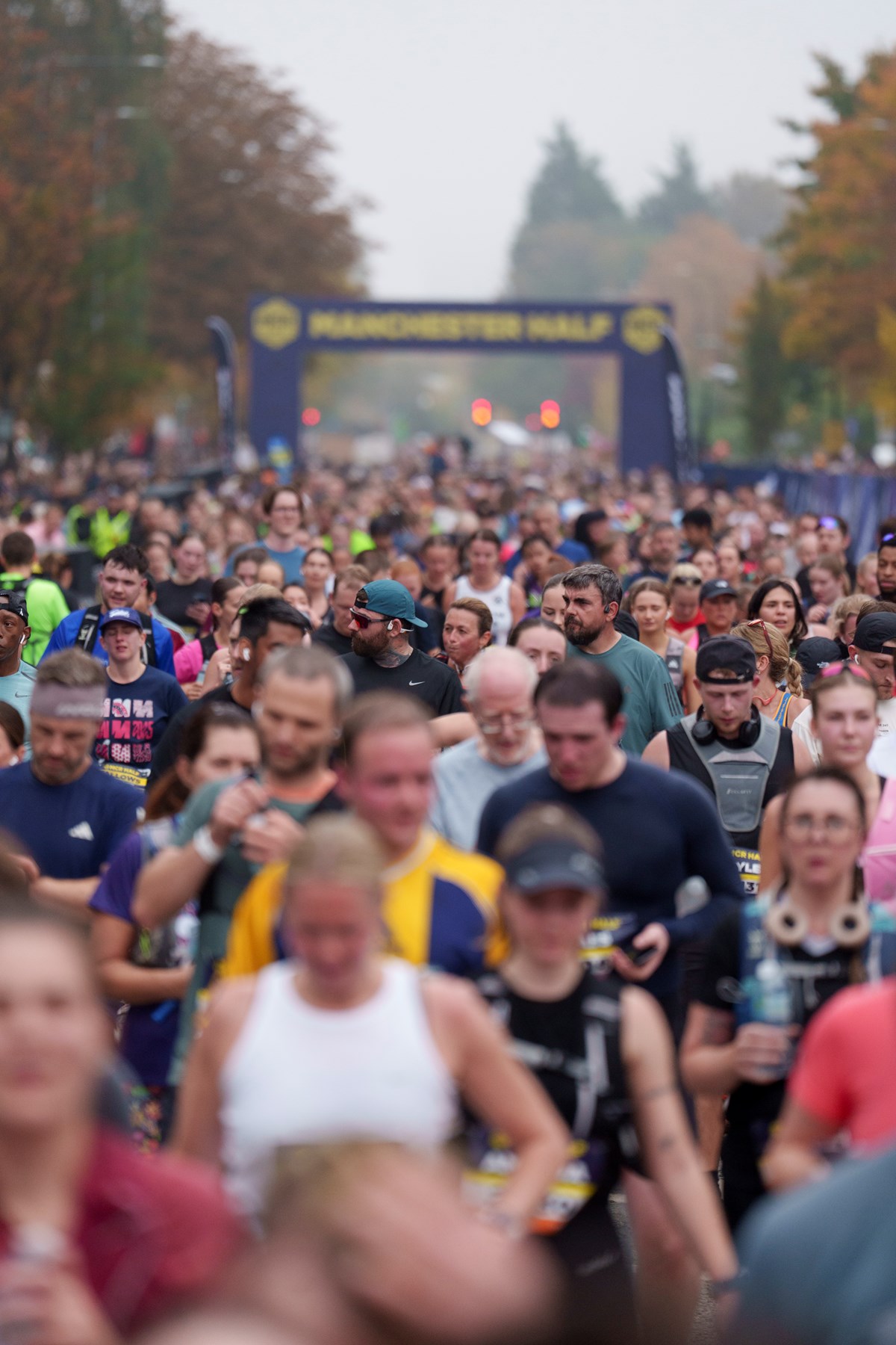 A large crowd of runners setting off beneath the Manchester Half start gantry.