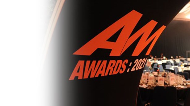 'AM Awards 2021' banner in front of tables laid out for an awards dinner.