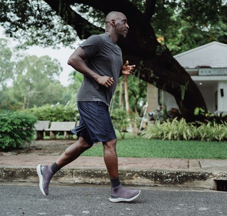 Person running down a street to boost their physical health