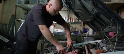 Vehicle technician working to fix a car. Work forms an important part of life and can have positive impacts on health and wellbeing 