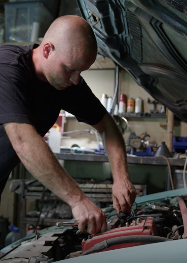 Work health and wellbeing. Man checking under the bonnet of a car. Motor mechanic and technician fixing car in a garage