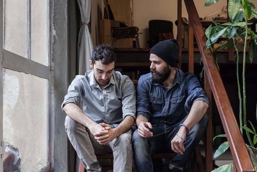 Two people sitting on a flight of stairs chatting to tackle loneliness