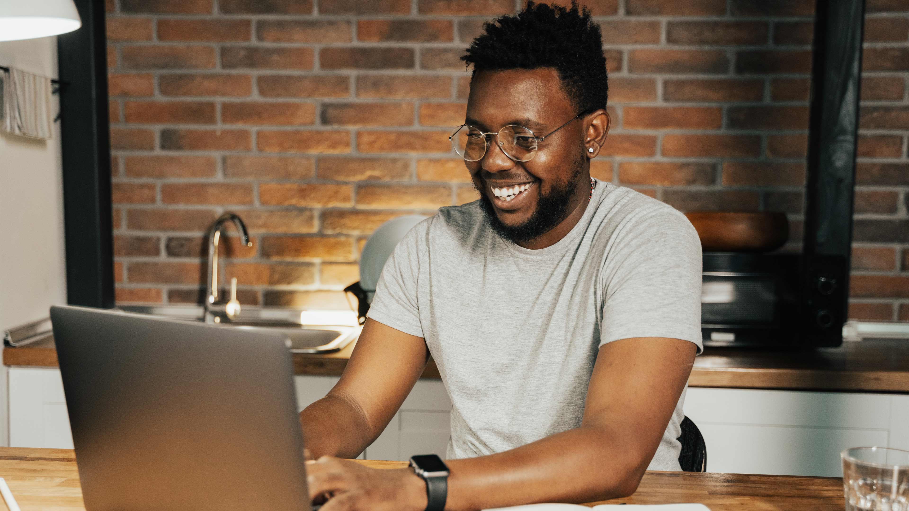 Happy man working from home in his kitchen using a laptop. There are benefits and challenges for working from home