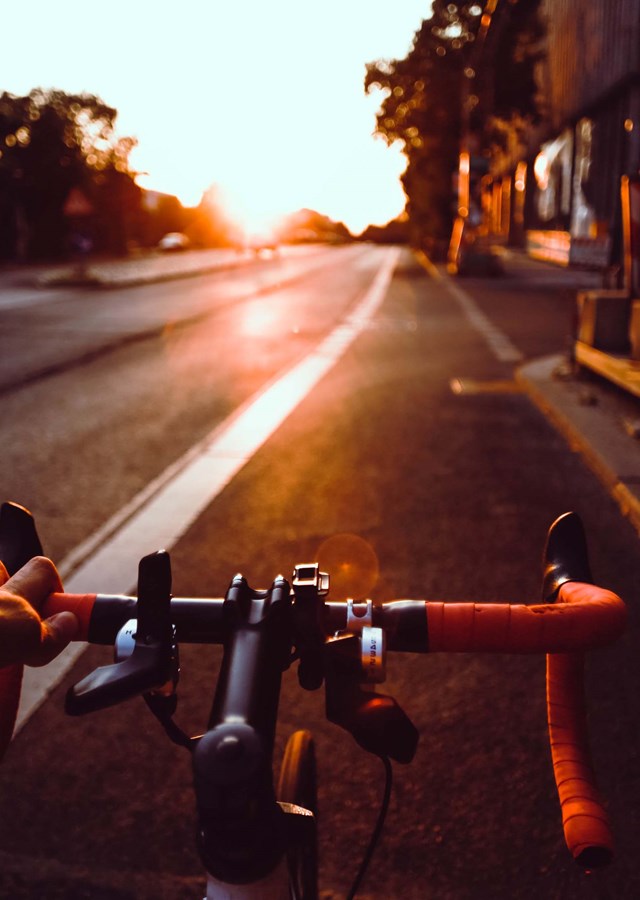Person cycling down a road on their way to work as the sun rises 