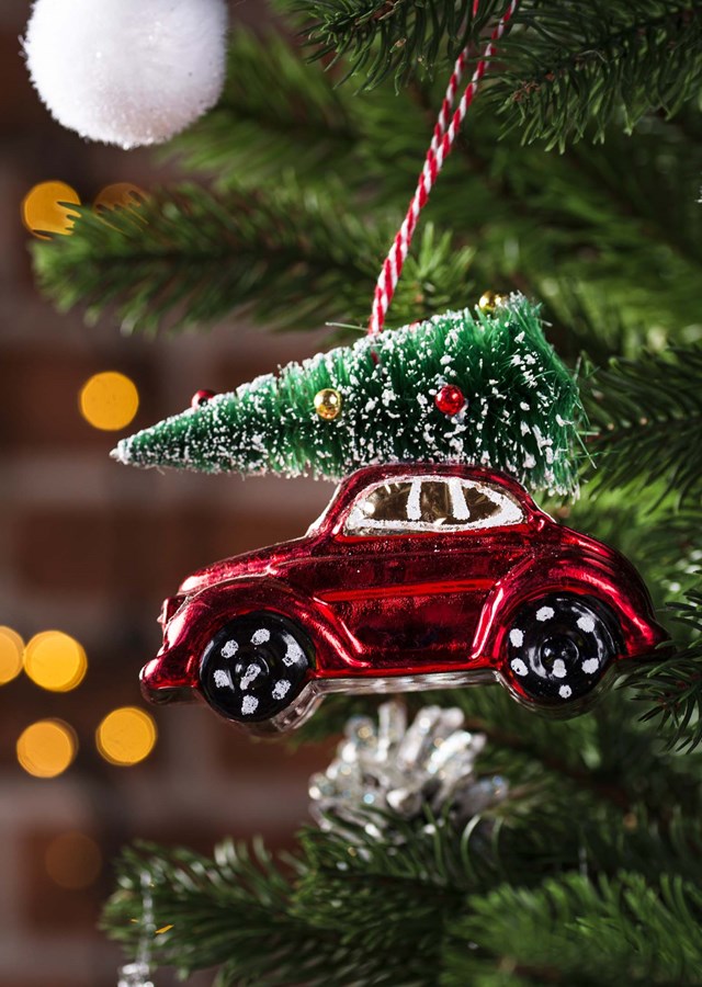 A red car with a tree on top ornament hanging on a Christmas tree