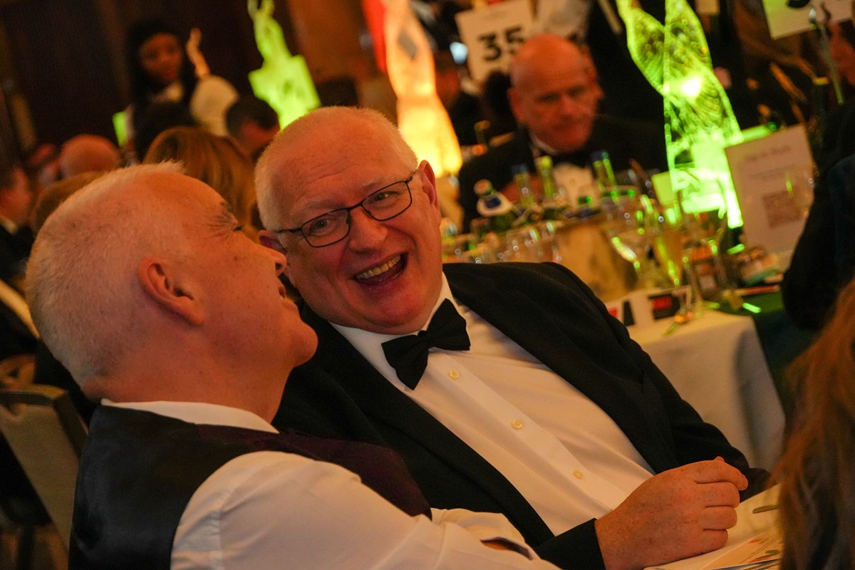 Two men in black tie laughing together at a table during the Ben Ball.