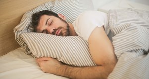 Man in deep sleep in light room. Improving sleep as a shift worker trying to get sleep at different times of the day and when others are awake