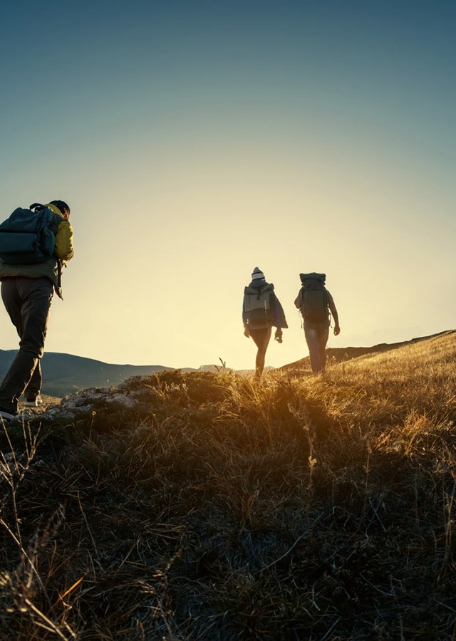 Group of four hikers, walking up a mountain in England at sunset
