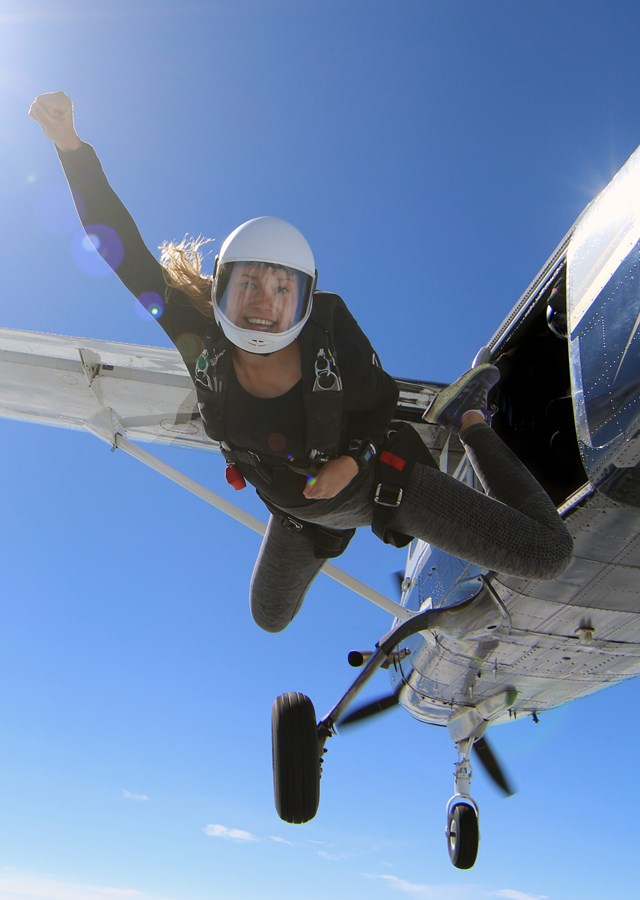 Female skydiver jumping out of a flying aeroplane in beautiful blue sky 