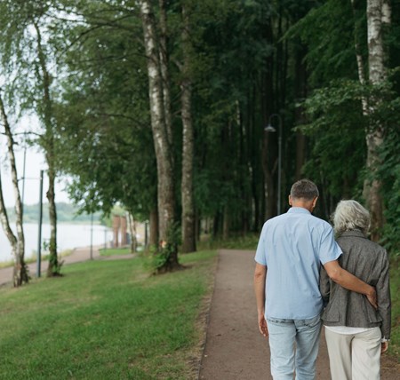 Two people walking together with their arm around each other showing support