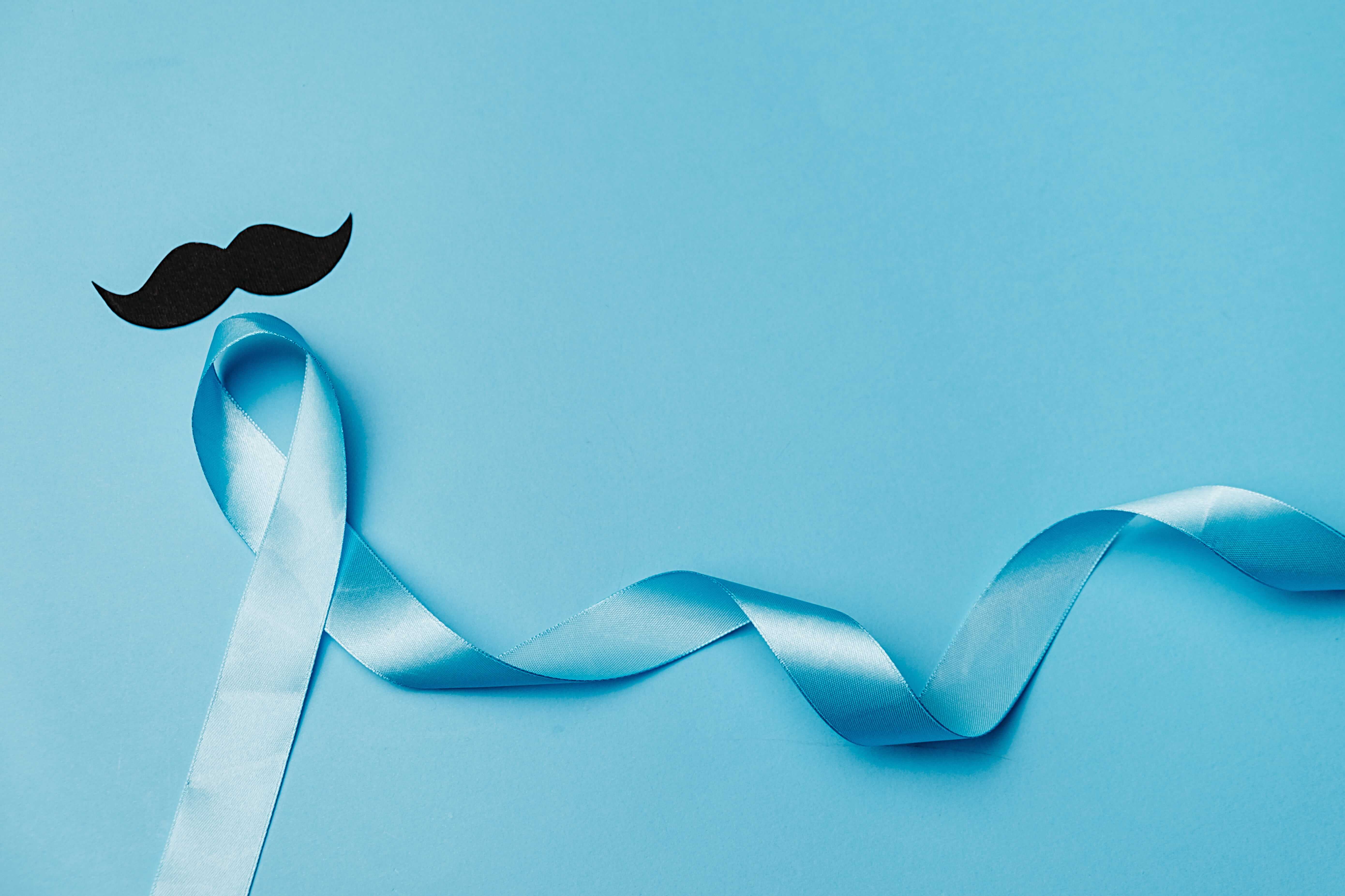 Top view on Light blue ribbon with moustache on blue background to symbolise Men's Health Awareness