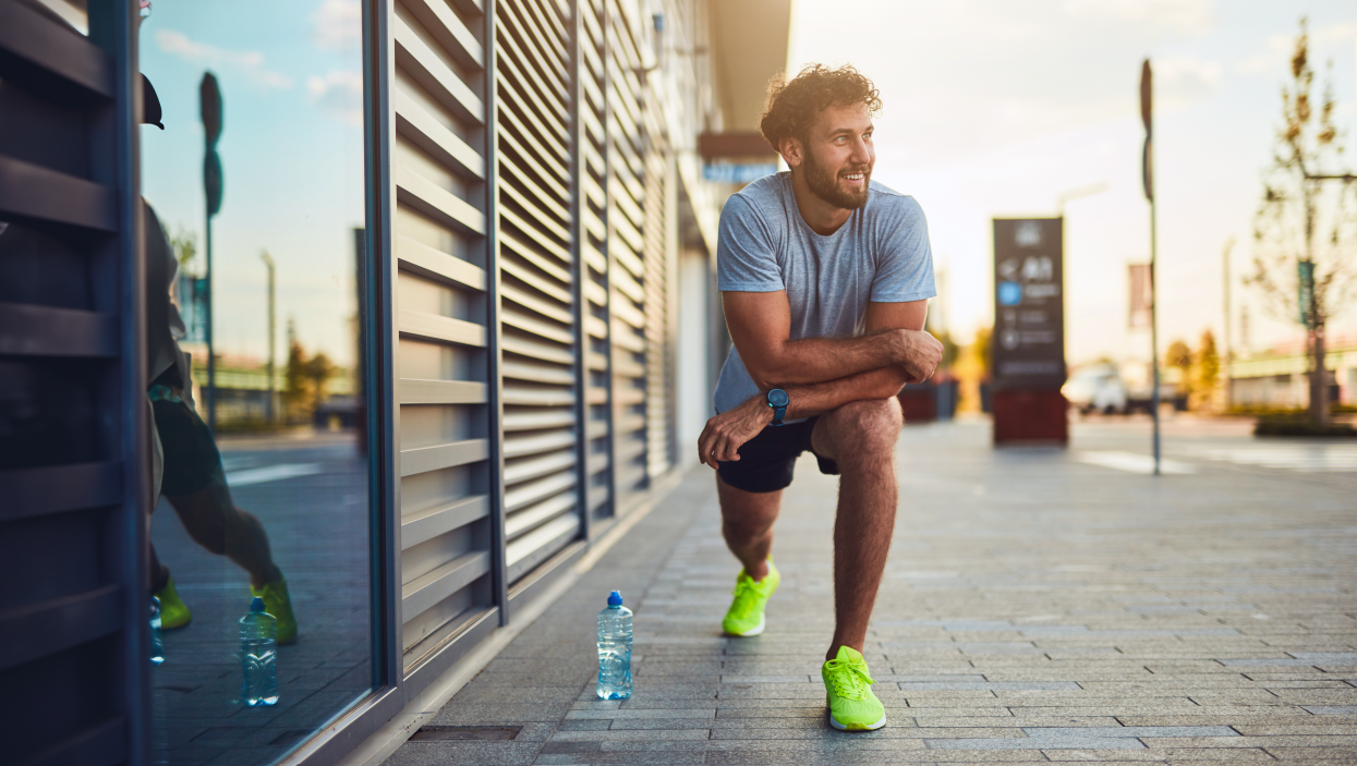 Young man exercising/stretching in an urban area. Practicing good self care to look after his health and wellbeing