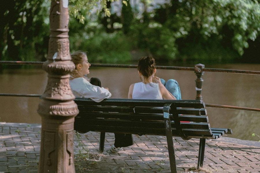 2 friends chatting on a park bench