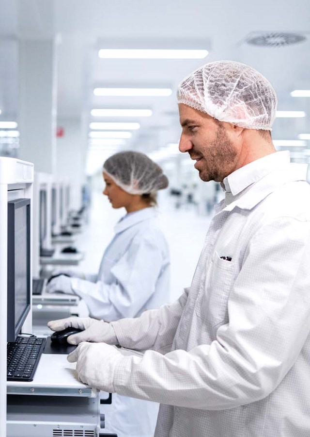 Employees working on machine computers at a factory assembly line.