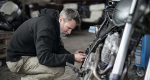 A mechanic working on a motorbike in a garage.