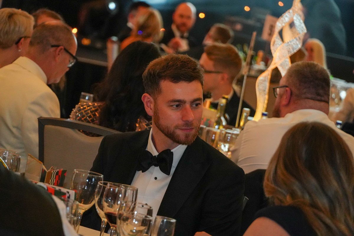 Guest in black tie seated at a table of wine glasses among other guests at the Ben Ball.