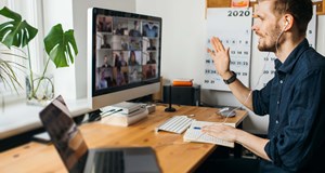 Man working from home in an office having an online meeting, connecting with colleagues