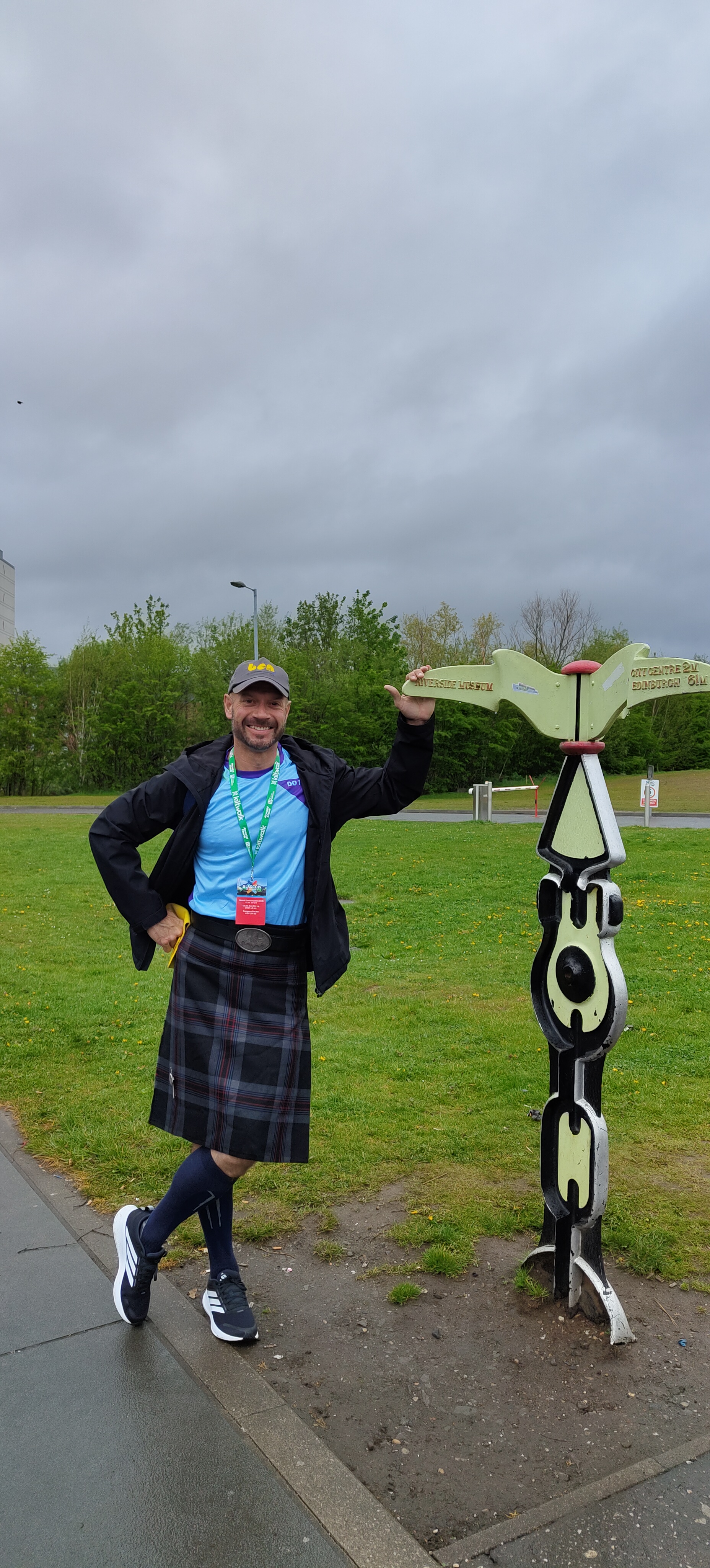 Man standing next to sign in Kilt, ready to take on Kiltwalk for Ben.