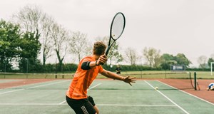 Person keeping fit by playing tennis outside using the tennis for free programme