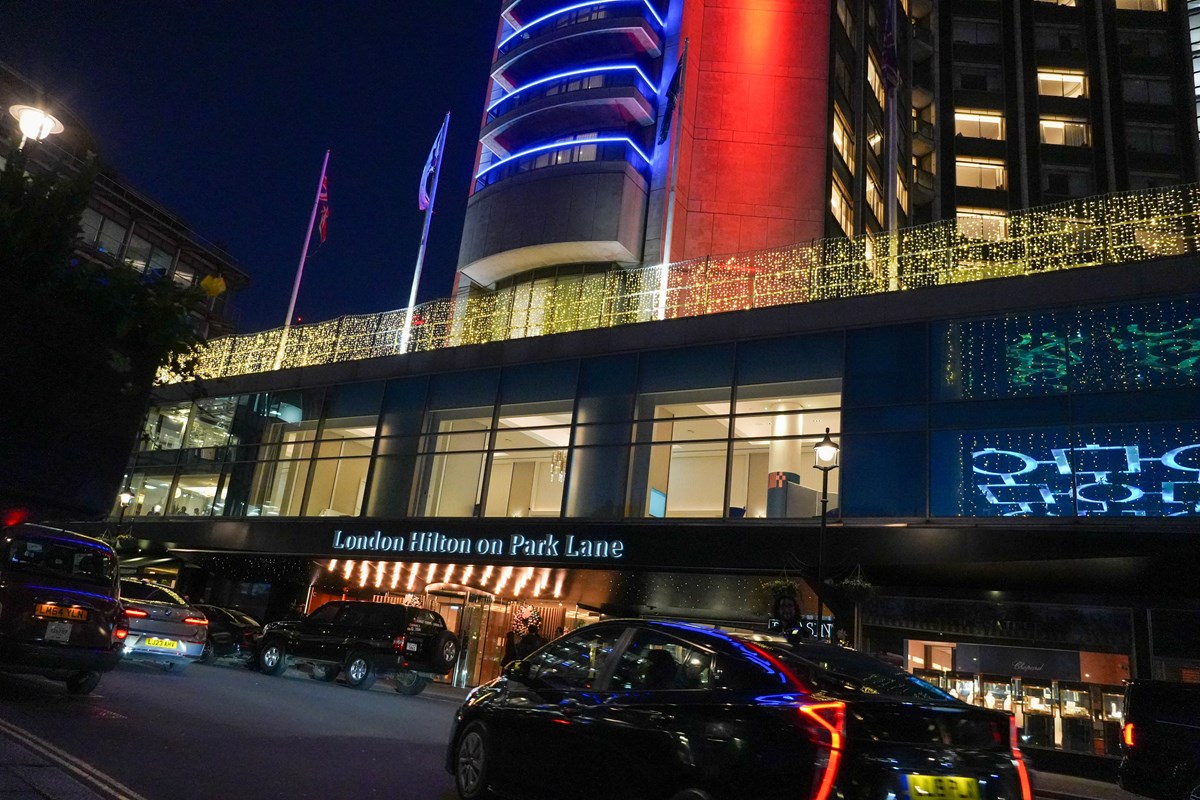 The London Hilton on Park Lane lit up at night, with cars and taxis outside the entrance.