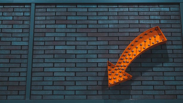 Orange arrow on a brick wall pointing to sign up information