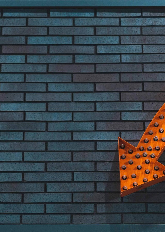 Orange arrow on a brick wall pointing to sign up information