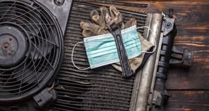 A face mask, spanner and gloves in a pile on a work bench