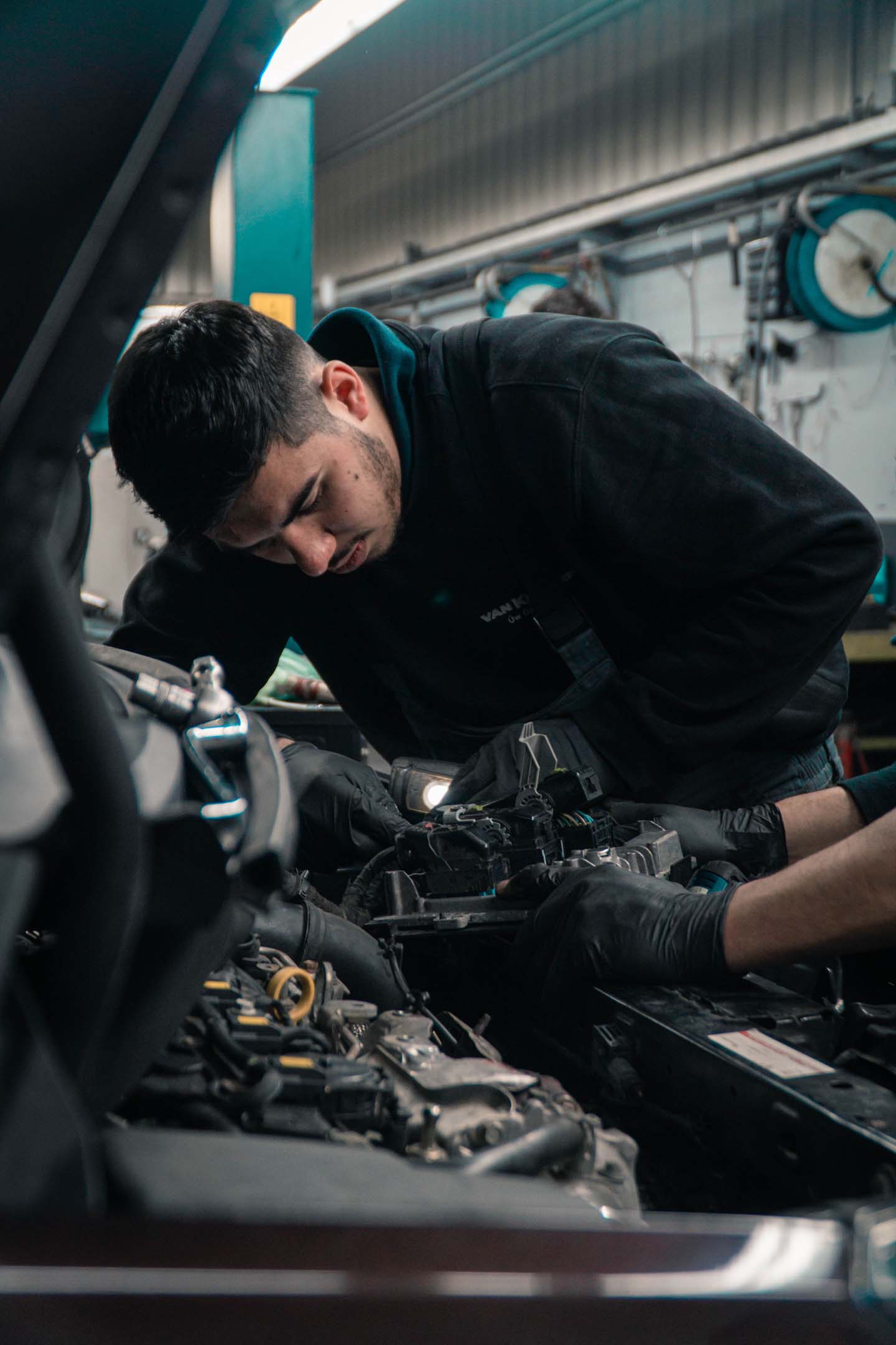 A mechanic (vehicle technician) bending over a car engine making repairs