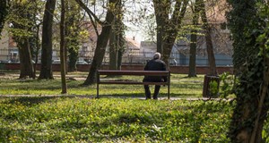 A person sitting alone on a bench in the park