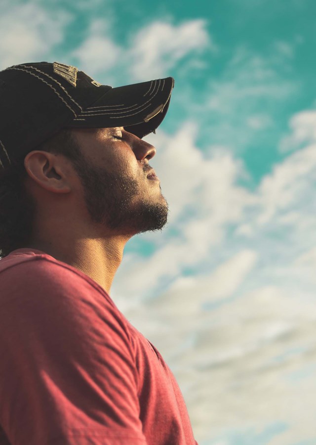 A person standing outside, facing the sun with their eyes closed just taking a moment