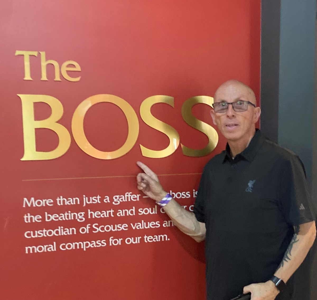 Paul pointing at a red display board reading 'The Boss' at a football stadium exhibition.