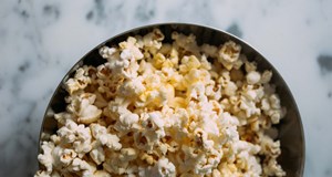 A large bowl of popcorn sitting on a table for a healthy snack