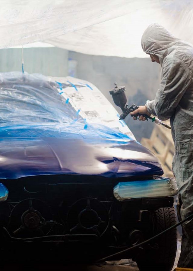 Car painter paints a car with a spray gun. Car painting at home.